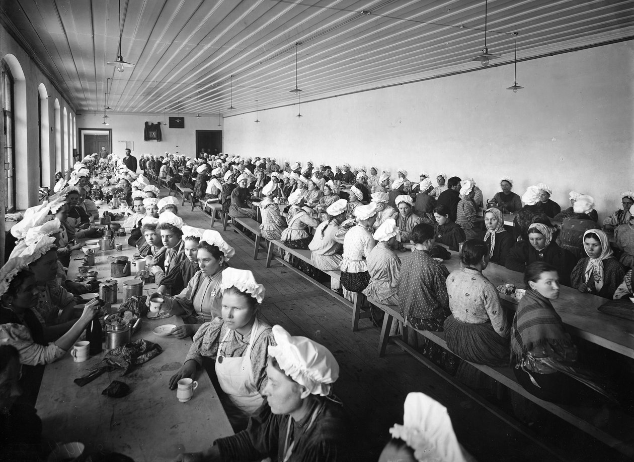 Kvinnliga arbetare i ett fabrikslager tar en middagsrast under överinseende av några manliga tillsyningsmän av Russian Photographer