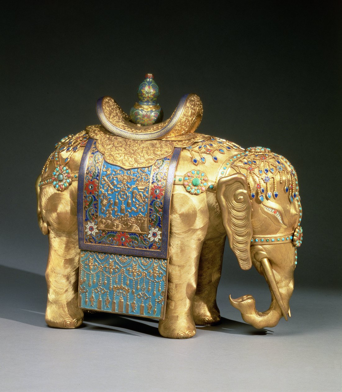 Figur av en elefant, med emaljföremål och cabochoner av korall och turkos, sadelduk dekorerad med buddhistiska emblem, Chien Lung-perioden, ca 1780 (förgylld brons, emalj, korall och turkos). av School Chinese