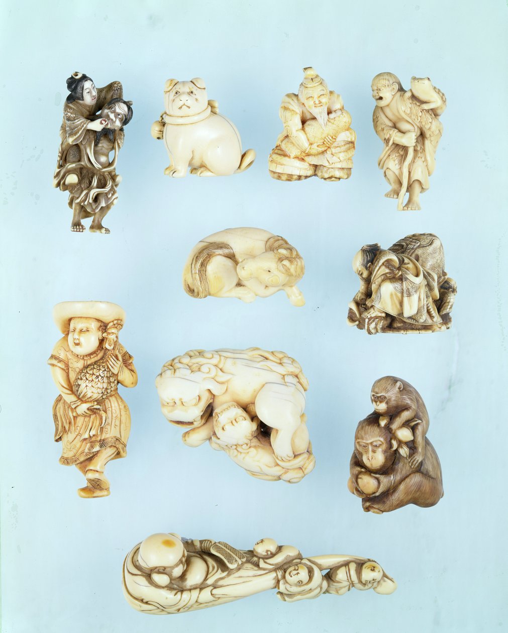 Urval av netsuke: Ikkuha Sennin bär skökan från Benares; sittande valp; Abe no Yasuneri håller en baby; Gamma Sennin; liggande häst; krigare som betvingar en förrymd oxe; stående holländare som håller en långstjärtad tupp; sittande apa som håller i en pers av Japanese School