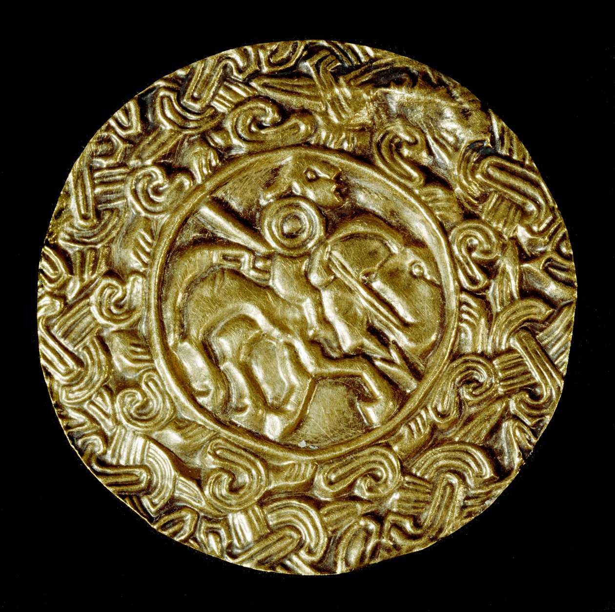 Medeltidens arkeologi (medeltiden). Barbarisk konst i Lombardiet: guldskiva. I centrum står ett helgon till häst med spjut och runt djurmotiv. Lombardkonst, ca 600. Dim: 47 cm Italien, Cividale del Friuli, Arkeologiska museet av School Lombard