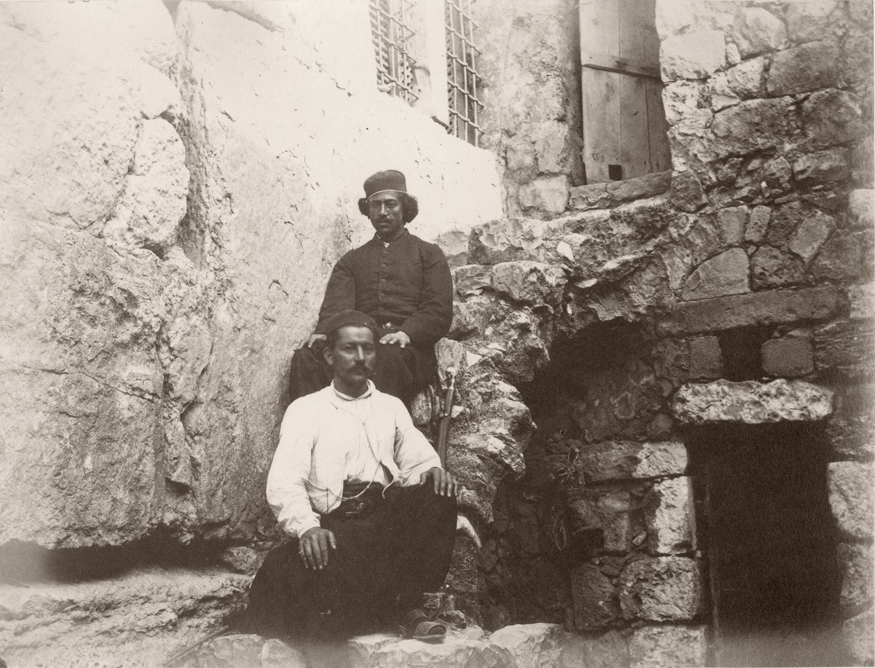 Två män sitter bredvid överstycket till Barclays port i den västra muren på Tempelberget, Jerusalem, 1866. av Sergeant Henry Phillips