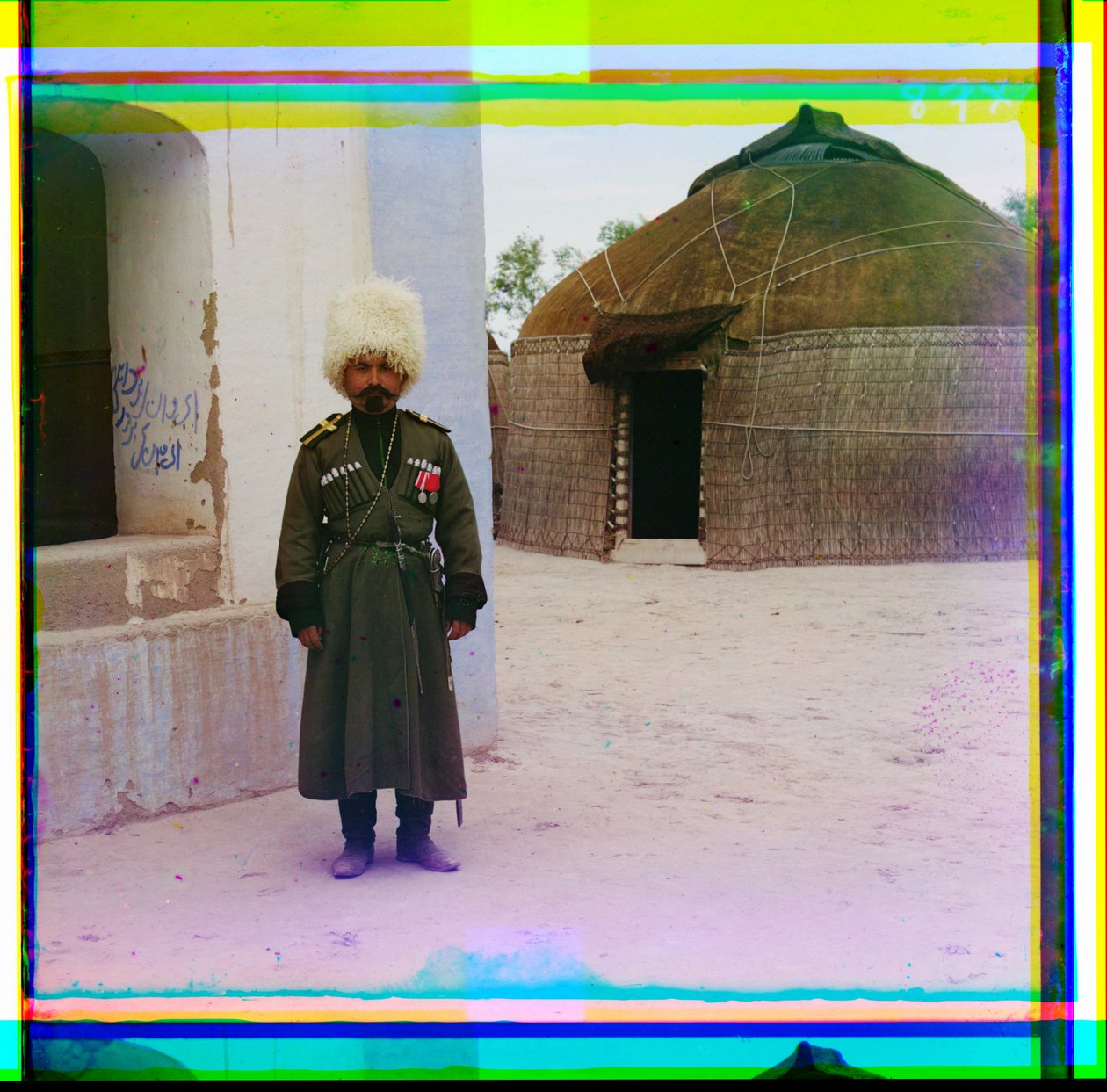 En beväpnad man i uniform står bredvid byggnaden med en jurta i bakgrunden, Ryssland, 1915 av Sergey Prokudin Gorsky