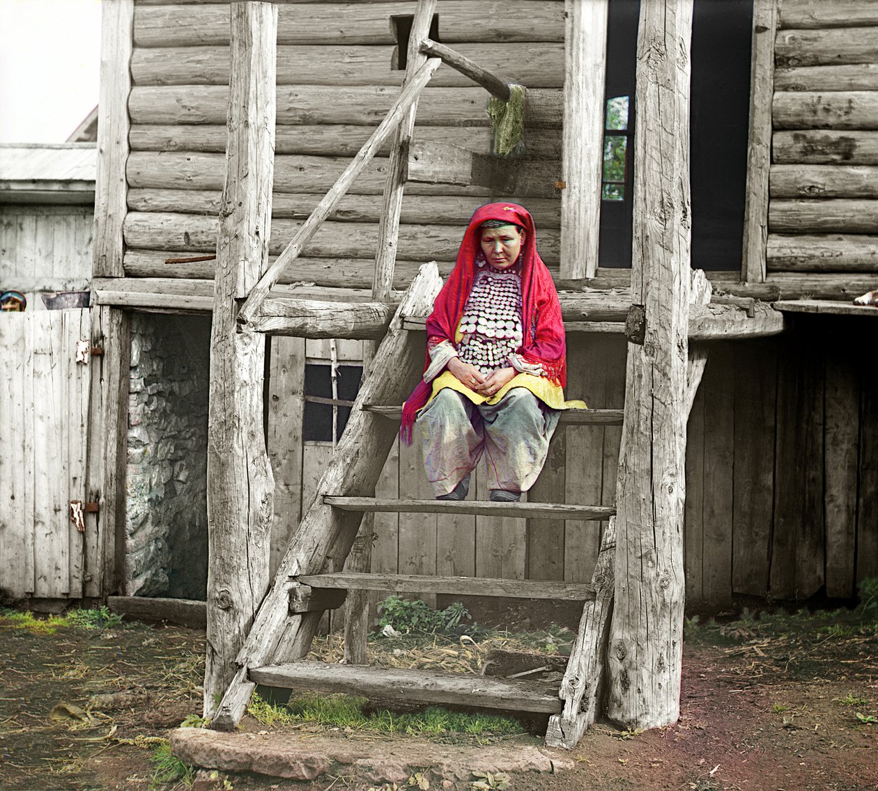 Bashkirskvinna i folkdräkt sitter på trappan till sitt trähus, Uralbergen, ryska imperiet, 1910 av Sergey Prokudin Gorsky