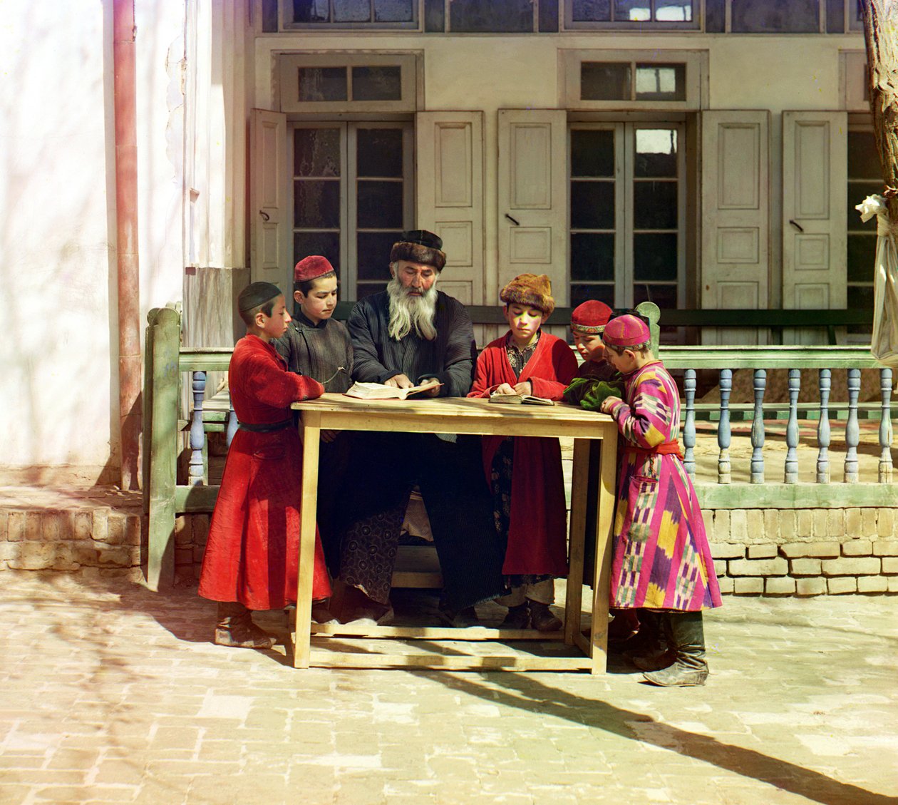 En grupp judiska barn med en lärare på ett bord framför ett hus, Samarkand, ryska imperiet, mellan 1905 och 1915 av Sergey Prokudin Gorsky