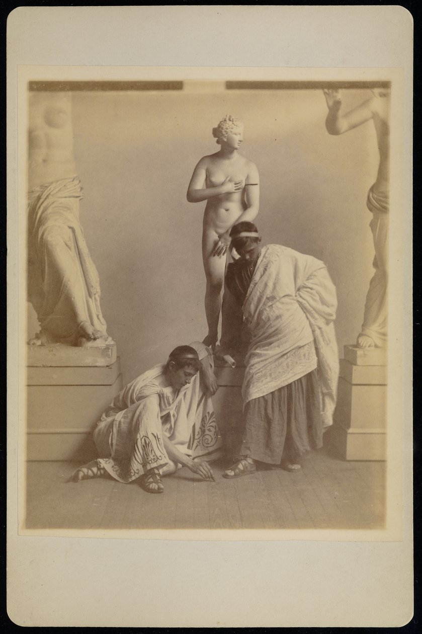 [Två manliga studenter i grekisk dräkt framför en gipsavgjutning av Afrodite i avgjutningsrummet på Pennsylvania Academy]. av Thomas Eakins