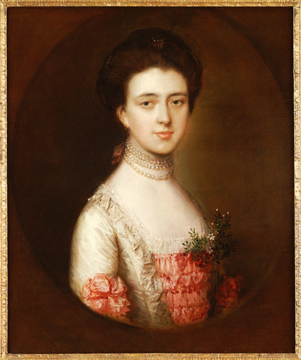 Porträtt av en dam, bystlängd, i en rosa och vit klänning trimmad med spets och ett pärlhalsband av Thomas Gainsborough