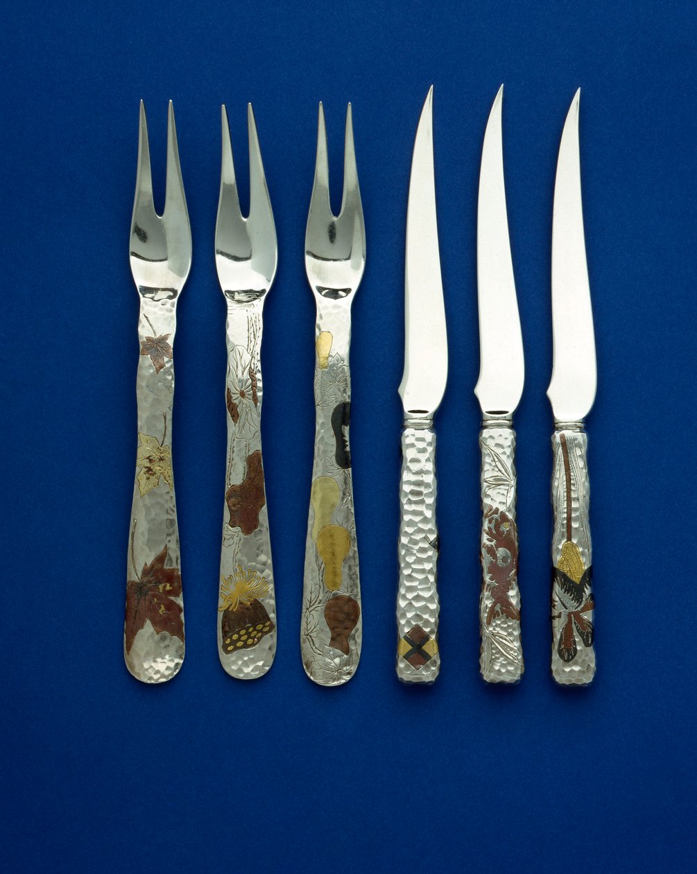 En del av en fin och sällsynt uppsättning av 36 dessertknivar och -gafflar, fläckhamrade handtag inlagda med patinerad koppar och färgat guld, med graverade detaljer av olika blom-, djur- och geometriska mönster, ca 1880 (koppar, guld) av Tiffany and Company