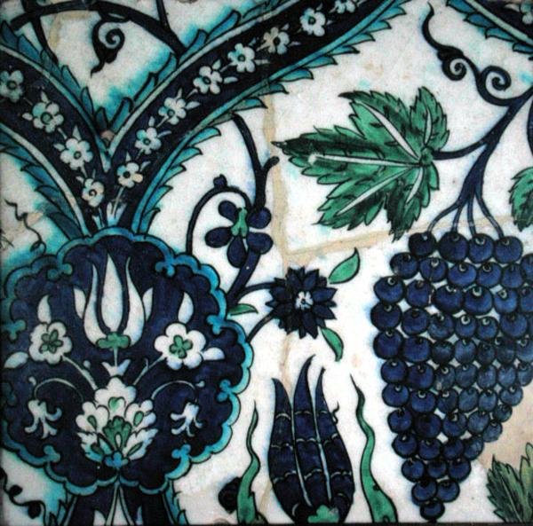 Iznik kakel med blommor och ett gäng vindruvor (lergods med färgad underglasyr) av Turkish School