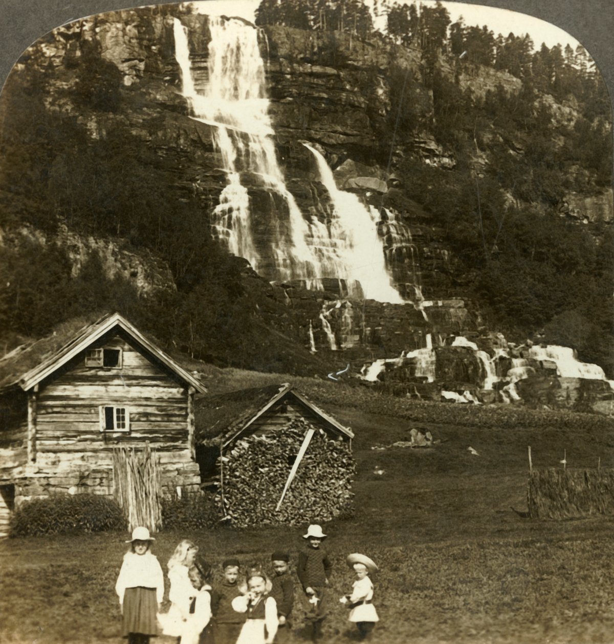 Barn som leker på en bonde åker med terrasserade Tvinde vattenfall, Vossevangen, Norge, c1905. av Unbekannt