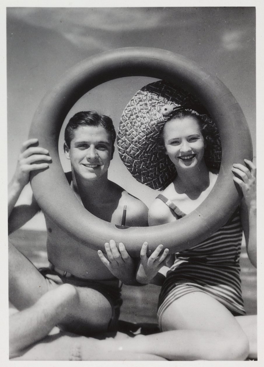 Man och kvinna tittar genom en gummiring på stranden, c 1935 av Unbekannt