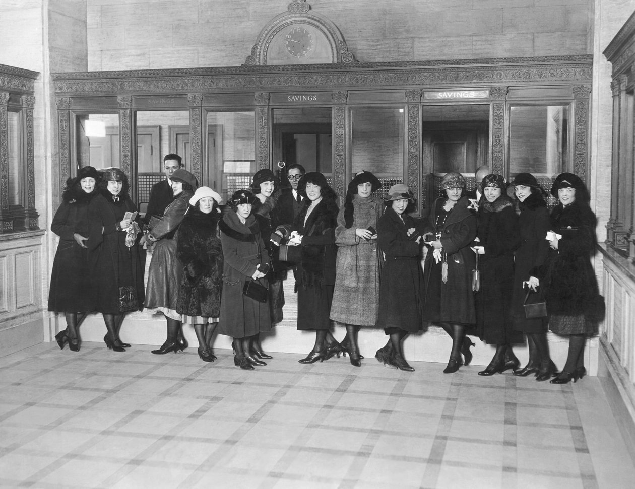 USA: c.1926 En grupp kvinnor som står vid kassans fönster för "Spara" på en bank. (s/v bild) av Unbekannt