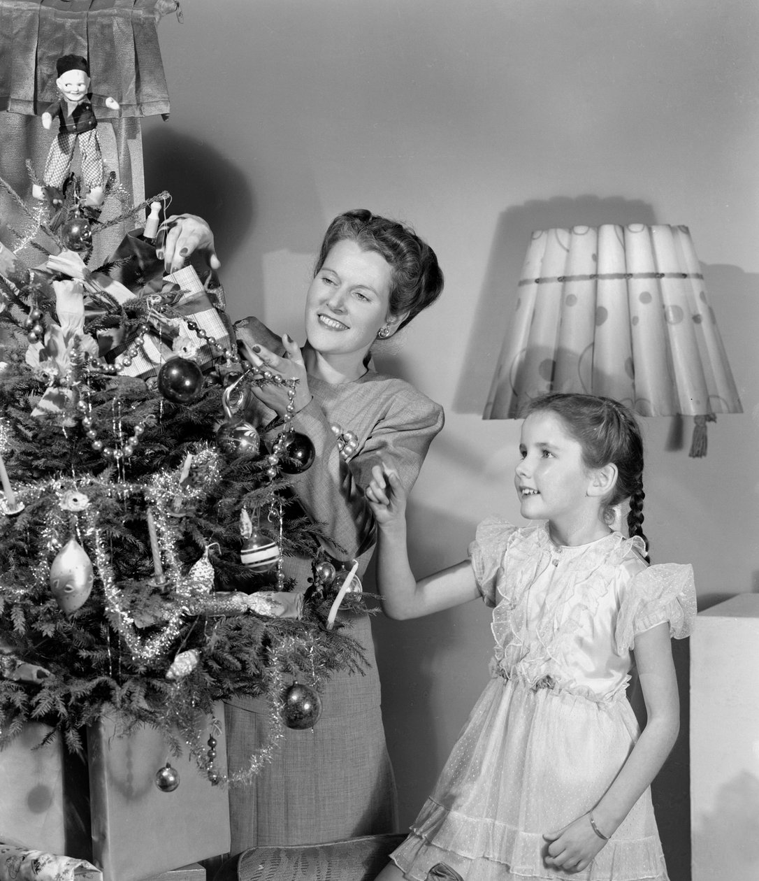 Kvinna och flicka dekorerar en julgran, c 1948 av Unbekannt