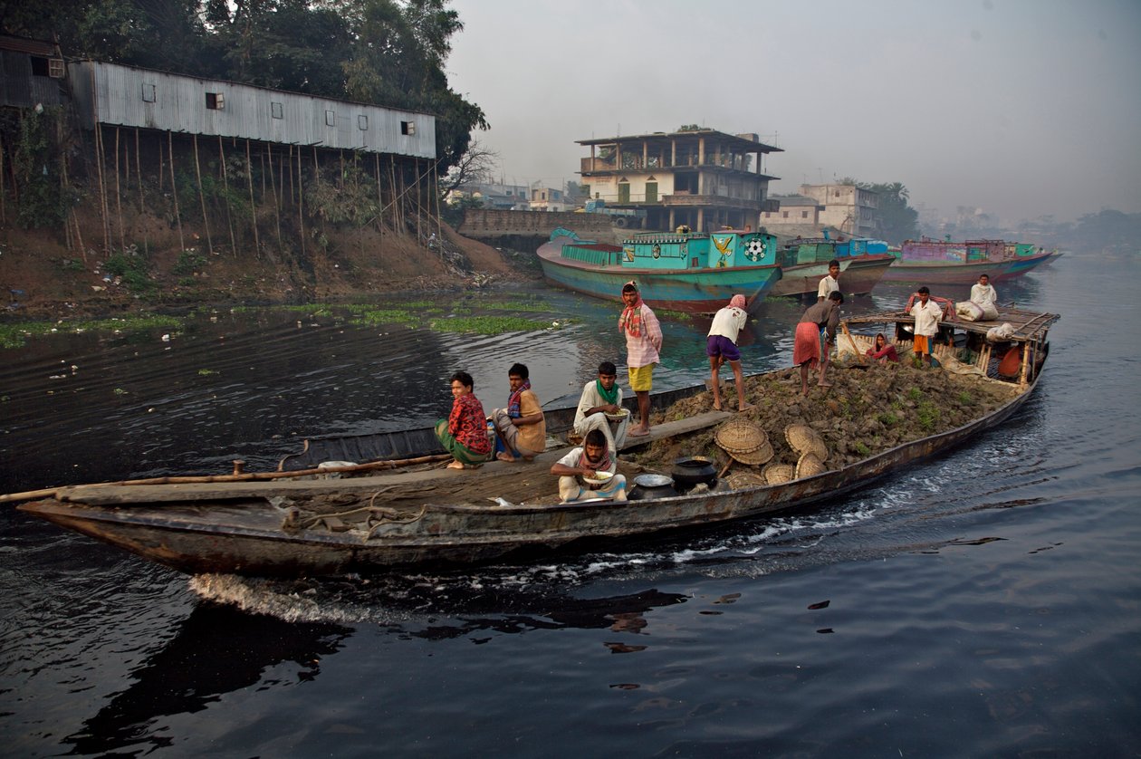 En båt som transporterar jord, som används för att fylla upp låg mark, genom Shitalakhya-floden, nära Tongi-bron, i utkanten av staden Dhaka. Bangladesh. 19 februari 2007. av Unbekannt Unbekannt