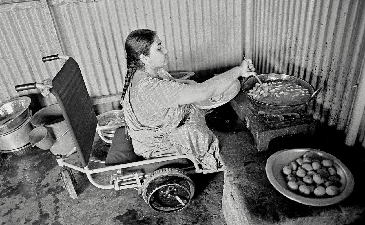 En fysiskt utmanad kvinna lagar mat åt sina kollegor på The Center for the Rehabilitation of the Paralysed, CRP i Savar, Dhaka, Bangladesh. 2005. av Unbekannt Unbekannt