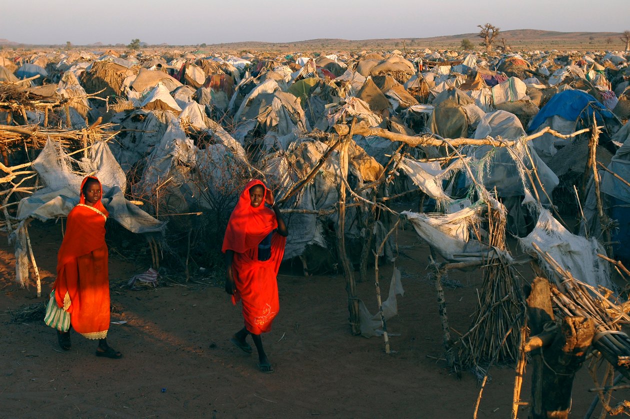 Klädda i knallröda kläder går kvinnor genom Otash-lägret för internflyktingar av Unbekannt Unbekannt