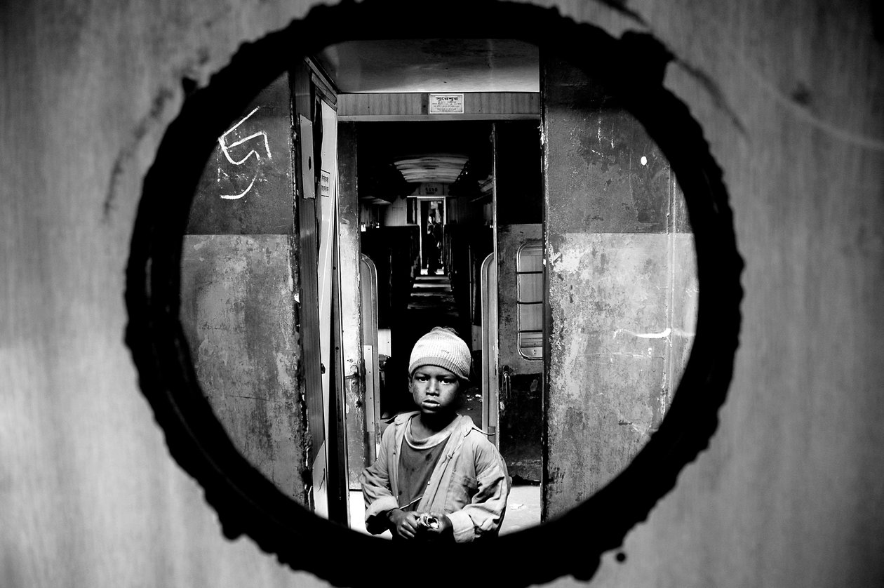Porträtt av ett gatubarn sett genom dörrhålet i kupén på ett tåg på Kamalapur järnvägsstation i Dhaka, Bangladesh. 5 januari 2007. av Unbekannt Unbekannt