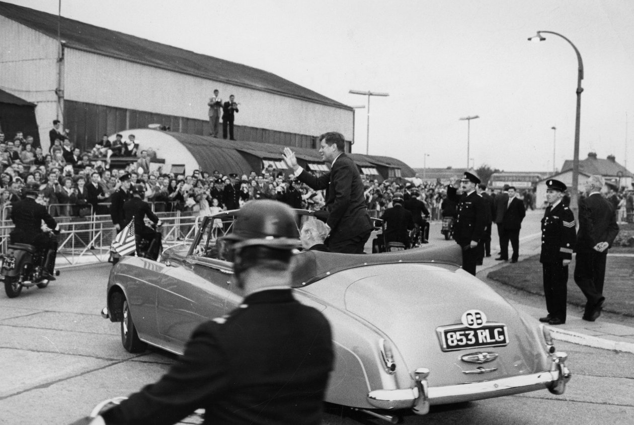 Efter att ha inspekterat en Naval Guard of Honor på Londons flygplats kör president Kennedy och Mr Macmillan iväg i en öppen bil. av Unbekannt