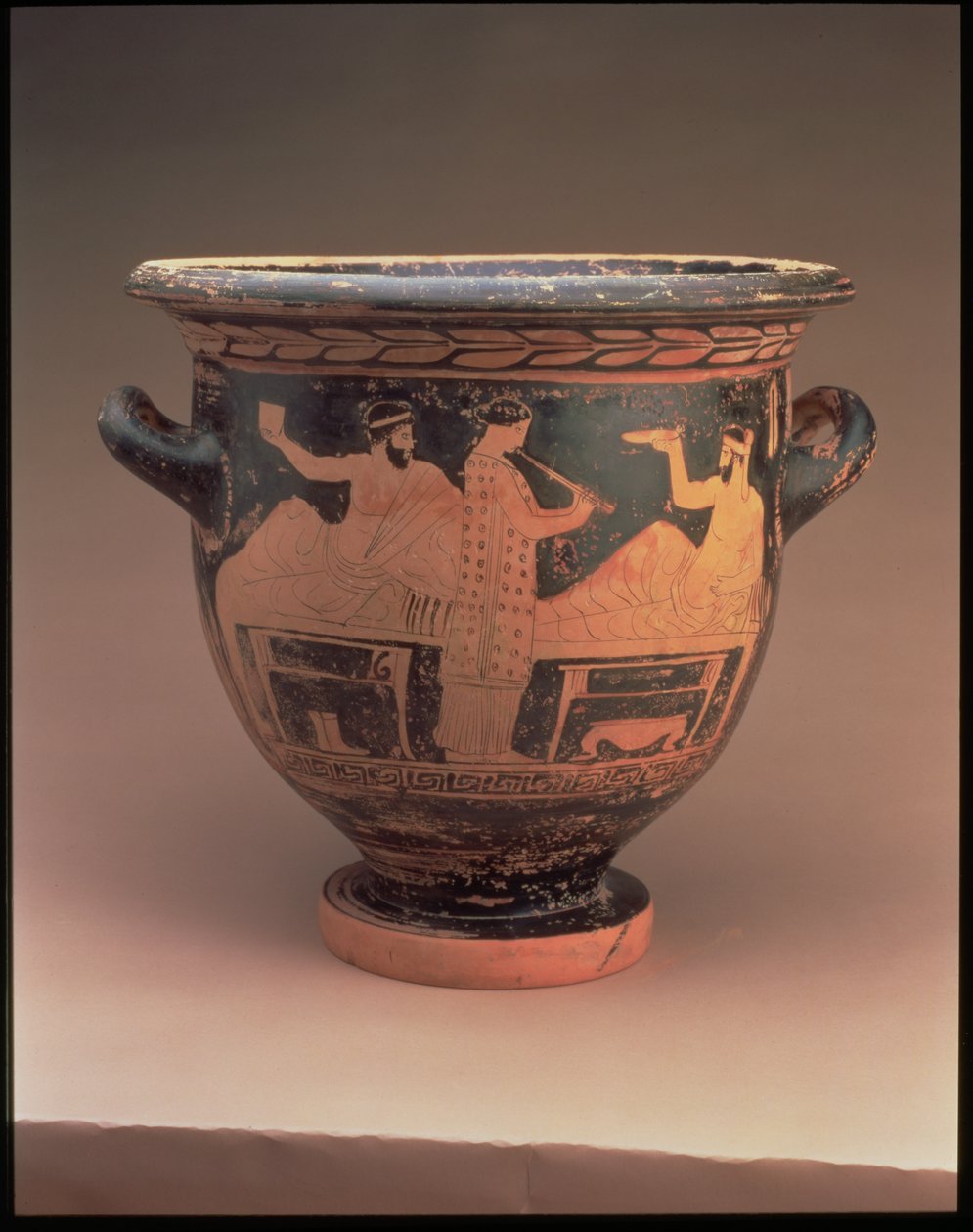 Attisk klockkrater med röd figur dekorerad med en symposiumscen av två liggande figurer och en stående flöjtspelare, grekisk, c.440-430 f.Kr. (keramik) av Unbekannt