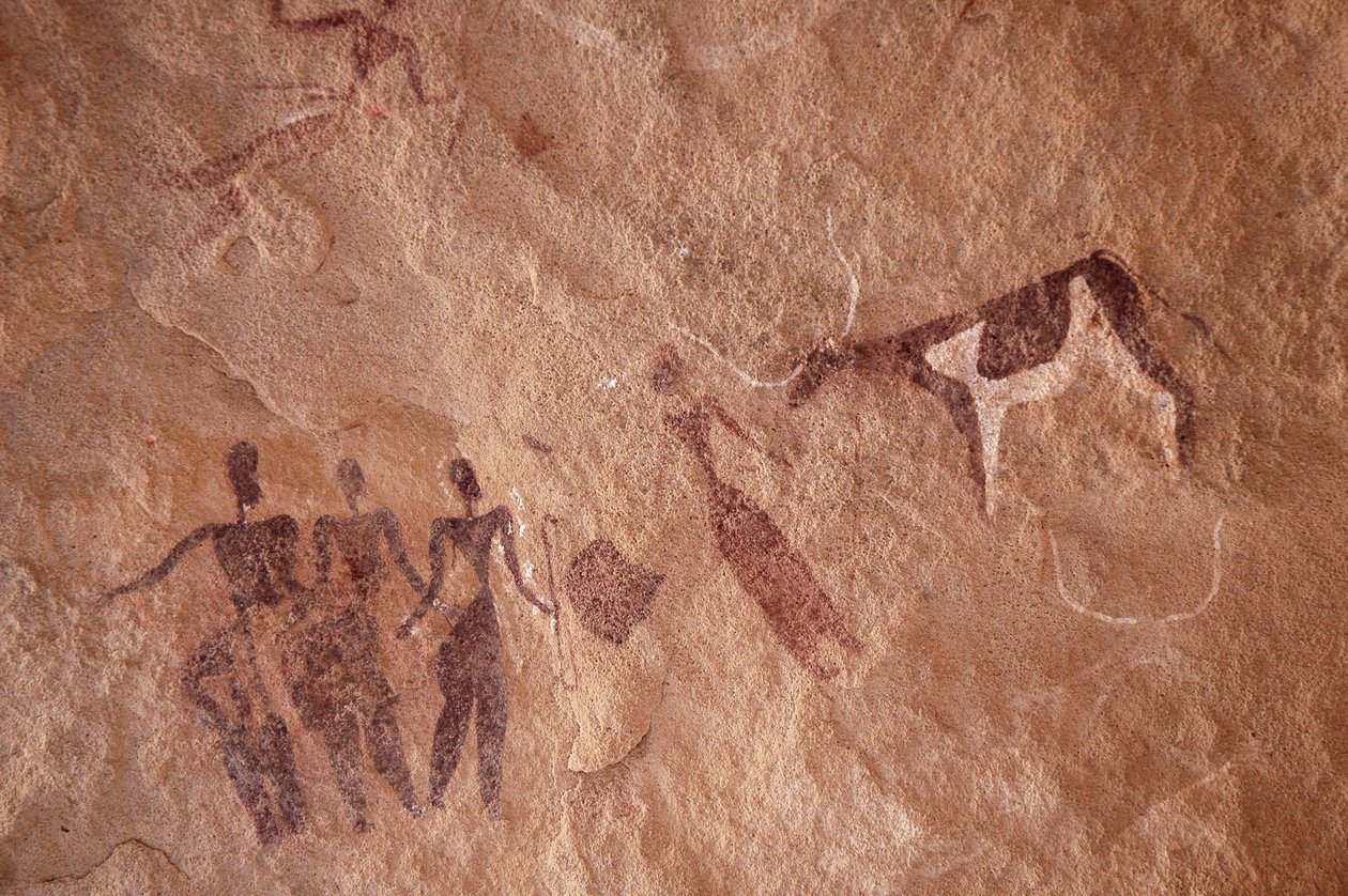 Stenkonst, förhistoria: Stenmålning av en grupp karaktärer och en tvåfärgad ko med stora horn i ett utsmyckat skydd, i Uweinat-massivet, Egypten. (Period från 8000 till 3000 år f.Kr.). Fotografi av Unbekannt
