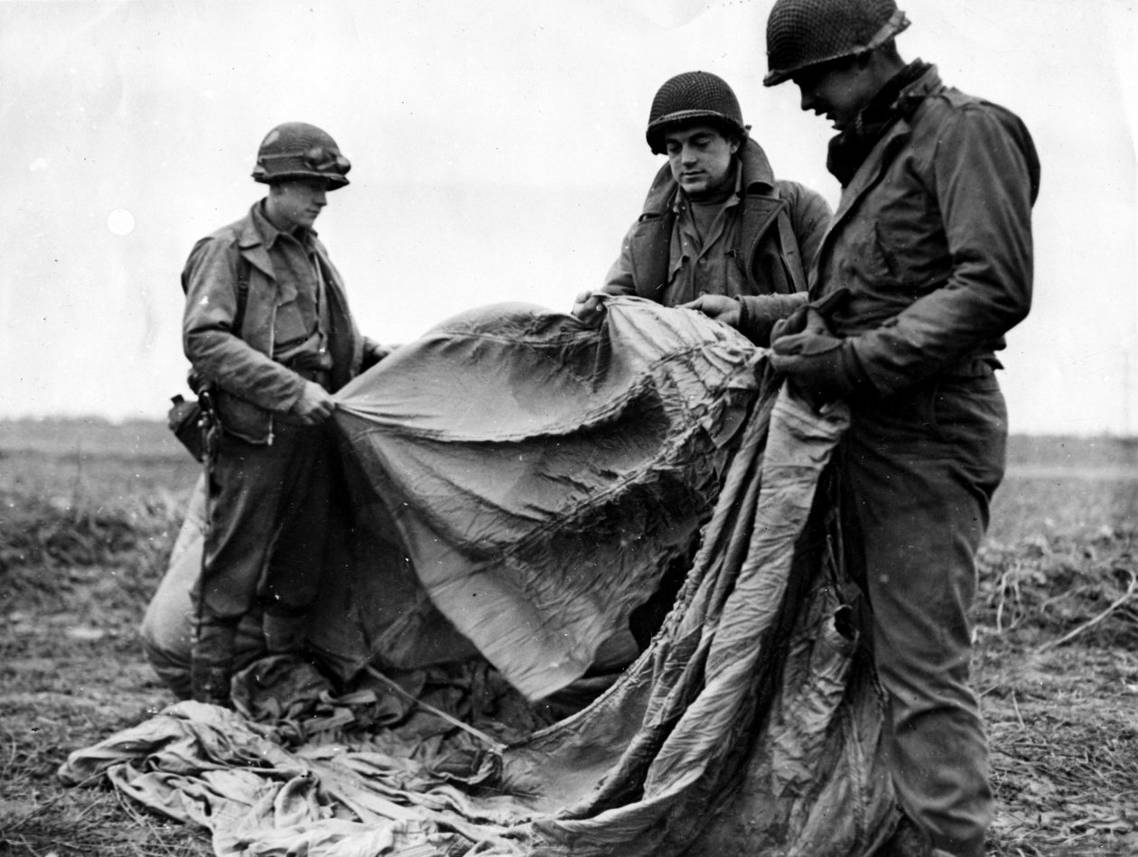 Andra världskriget (1939-1945) - Andra världskriget (WWII eller WW2): Nära Kornelmunster (Tyskland) 17 december 1944: Infanterister från den 1:a amerikanska armén undersöker en tysk fallskärm som användes natten före dagen för Operation Guards förfall i Rh av Unbekannt