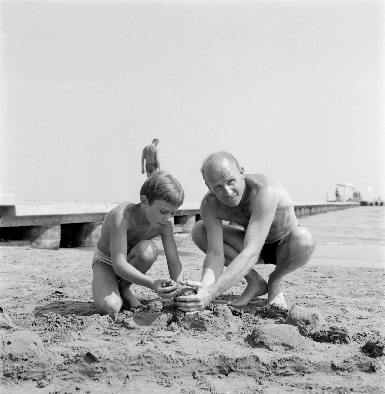 REGISSÖREN ALBERT LAMORISSE MED SIN SON SKÅDESPELARE PASCAL LAMORISSE PÅ VENICE LIDO BEACH - 1960 av Unbekannt