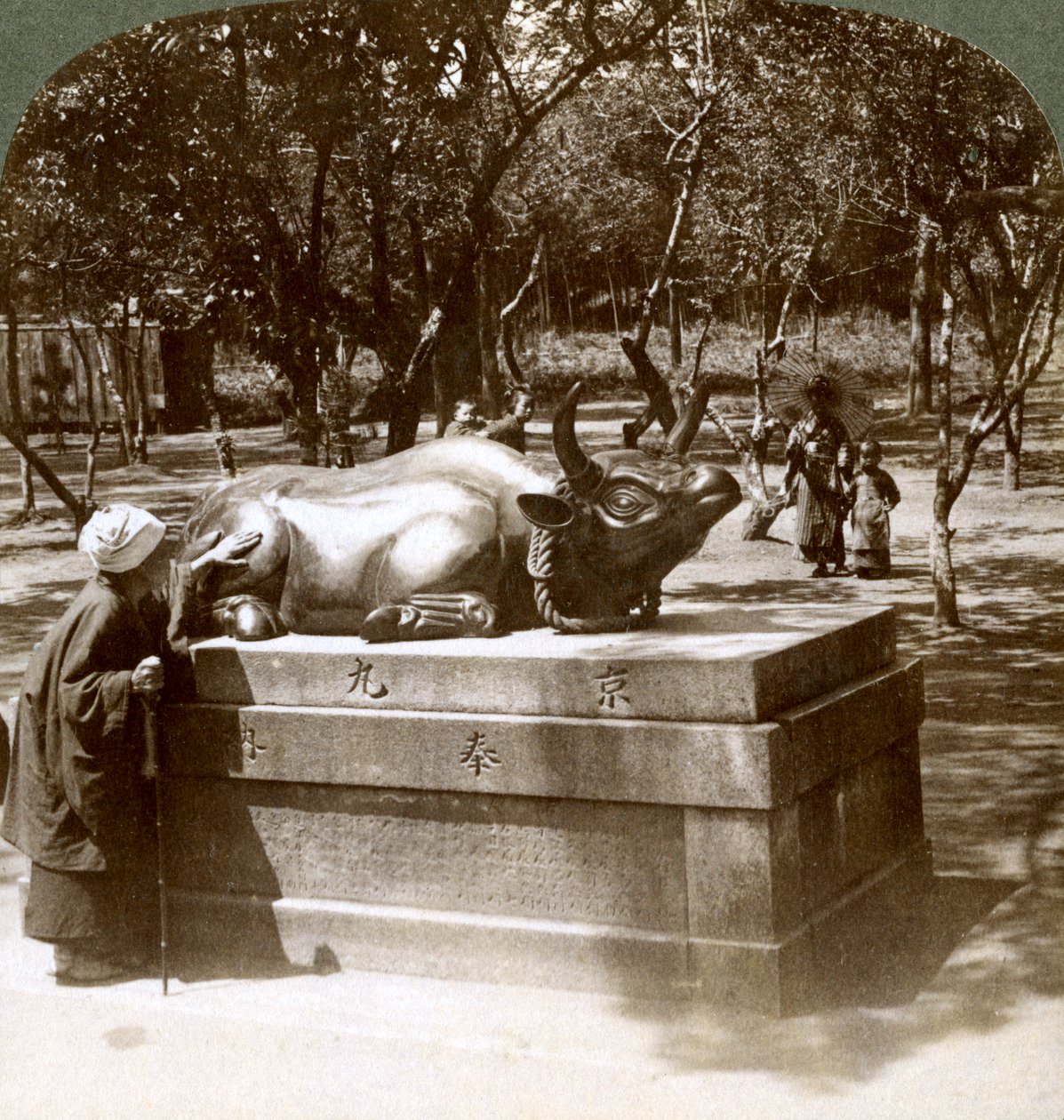 Troende kvinna som smeker en bronstjur för att bota reumatism, Kitano Tenjin-templet, Kyoto, Japan, 1904 av Underwood and Underwood