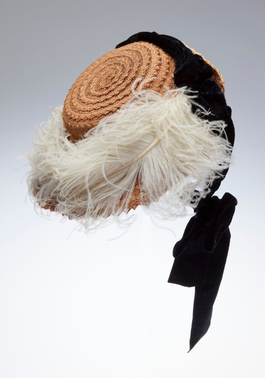 Straw bonnet with black velvet ribbon and white ostrich plume across brim. Made in Austria and worn by Sophie Tuholske av Unknown