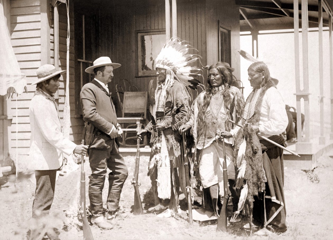 Tre cheyenner klädda i ceremoniell kostym och bärande vapen hälsar på en vit tillsammans med en tolk. sd. sent 1800-tal av Unknown artist
