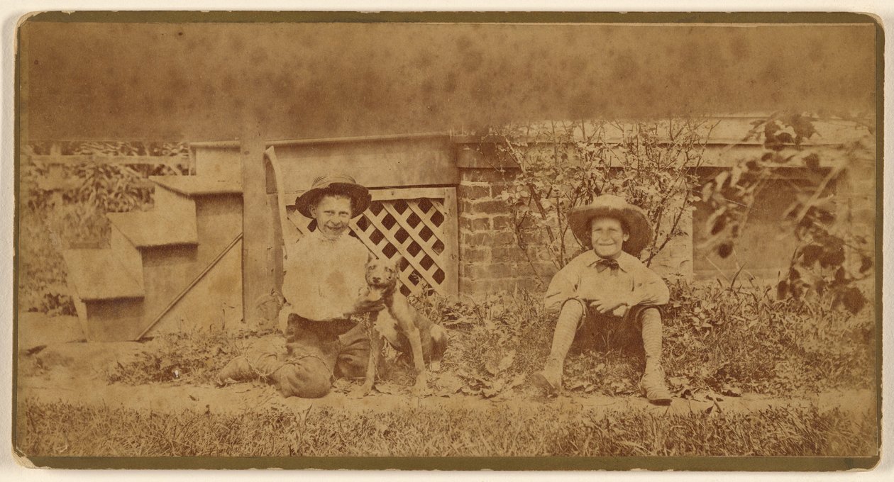 [Två pojkar sitter på marken med en hund] av Unknown artist
