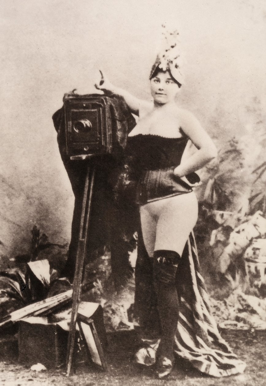 Porträtt av en delvis naken kvinna som lutar sig mot en antik kamera. av Unknown photographer