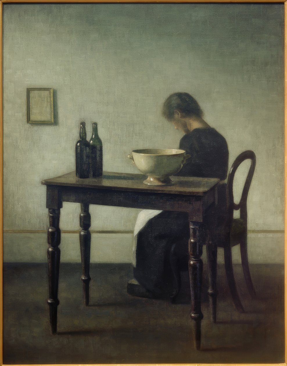 Kvinna som sitter bakom ett bord av Vilhelm Hammershoi