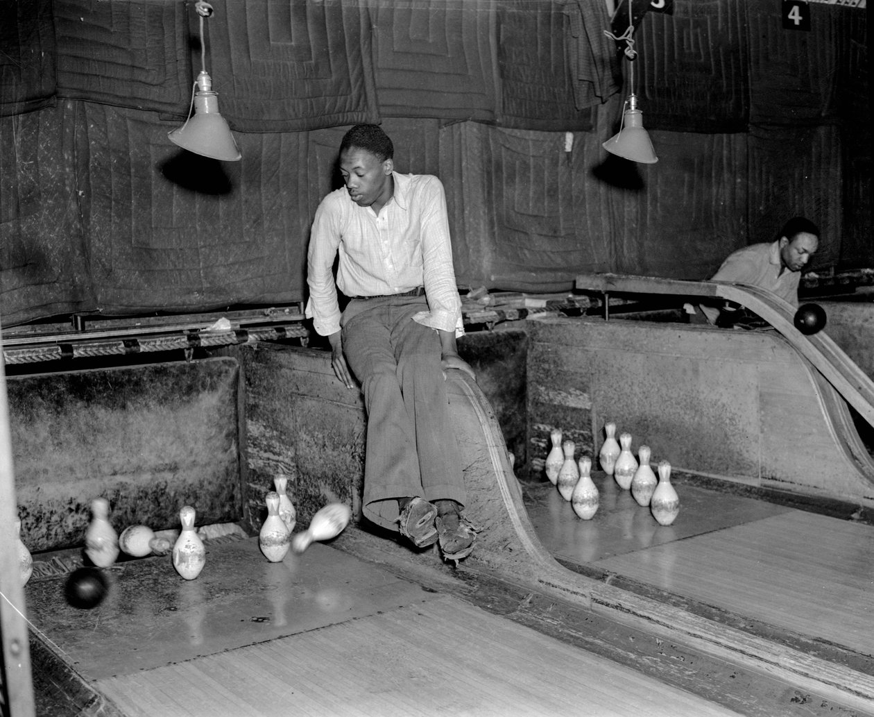 Afrikansk-amerikansk man deltar i tio käglor i bowlinghall, för att manuellt återställa käglan... av Volkmar Wentzel