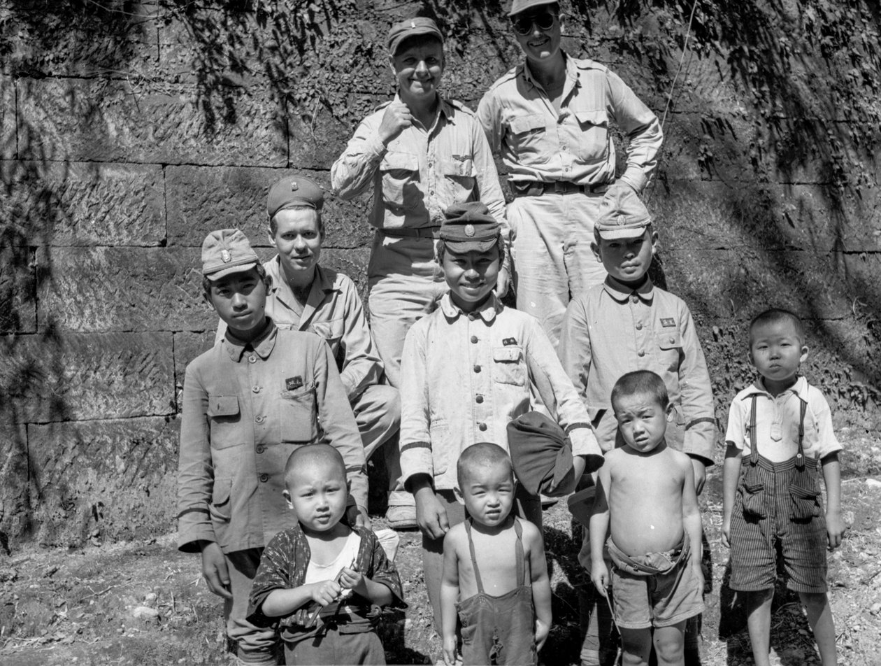 Amerikanska soldater med japanska familjer poserar tillsammans efter den japanska kapitulationen och... av Volkmar Wentzel