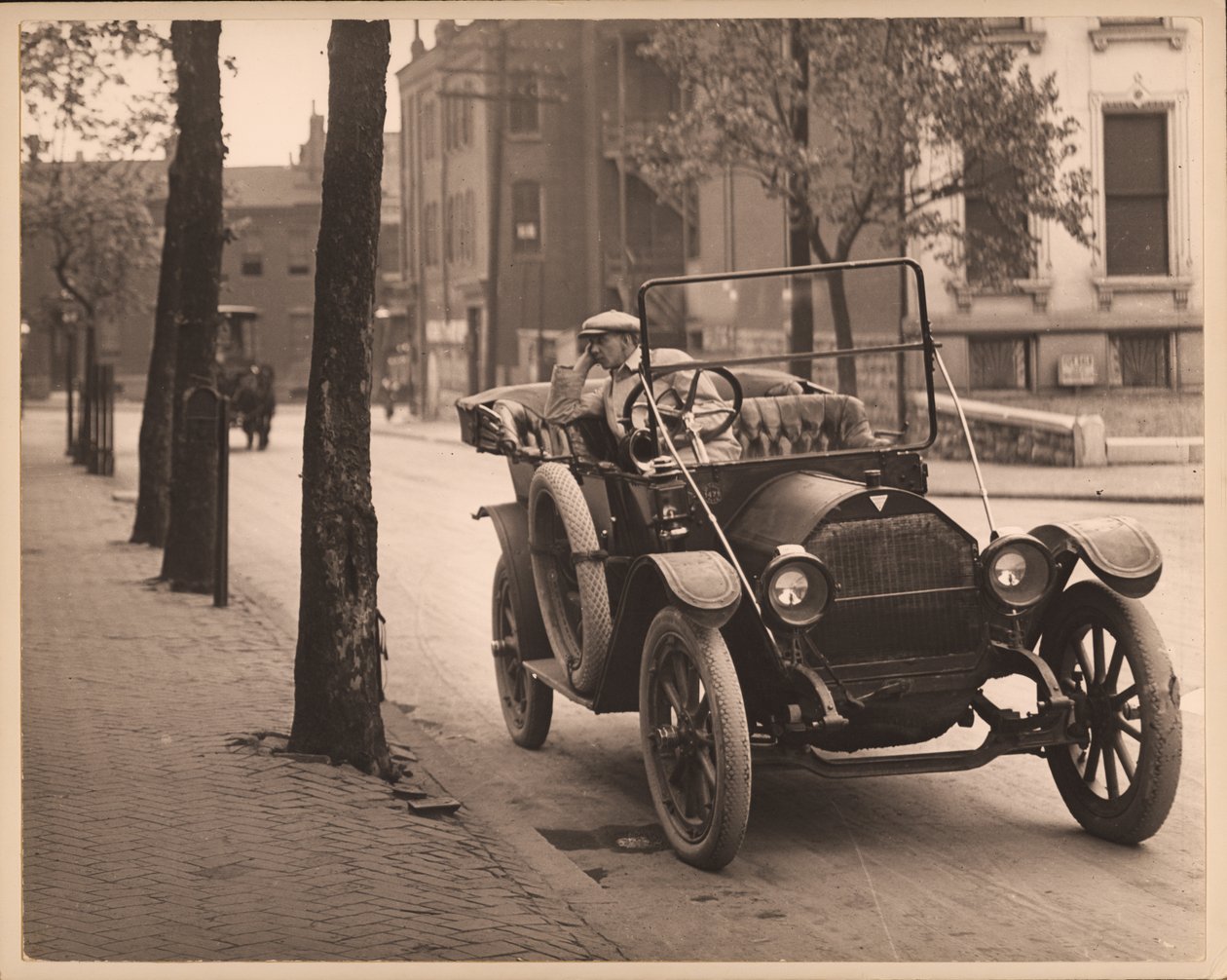 Man seated in automobile on unidentified street. av William G. Swekosky