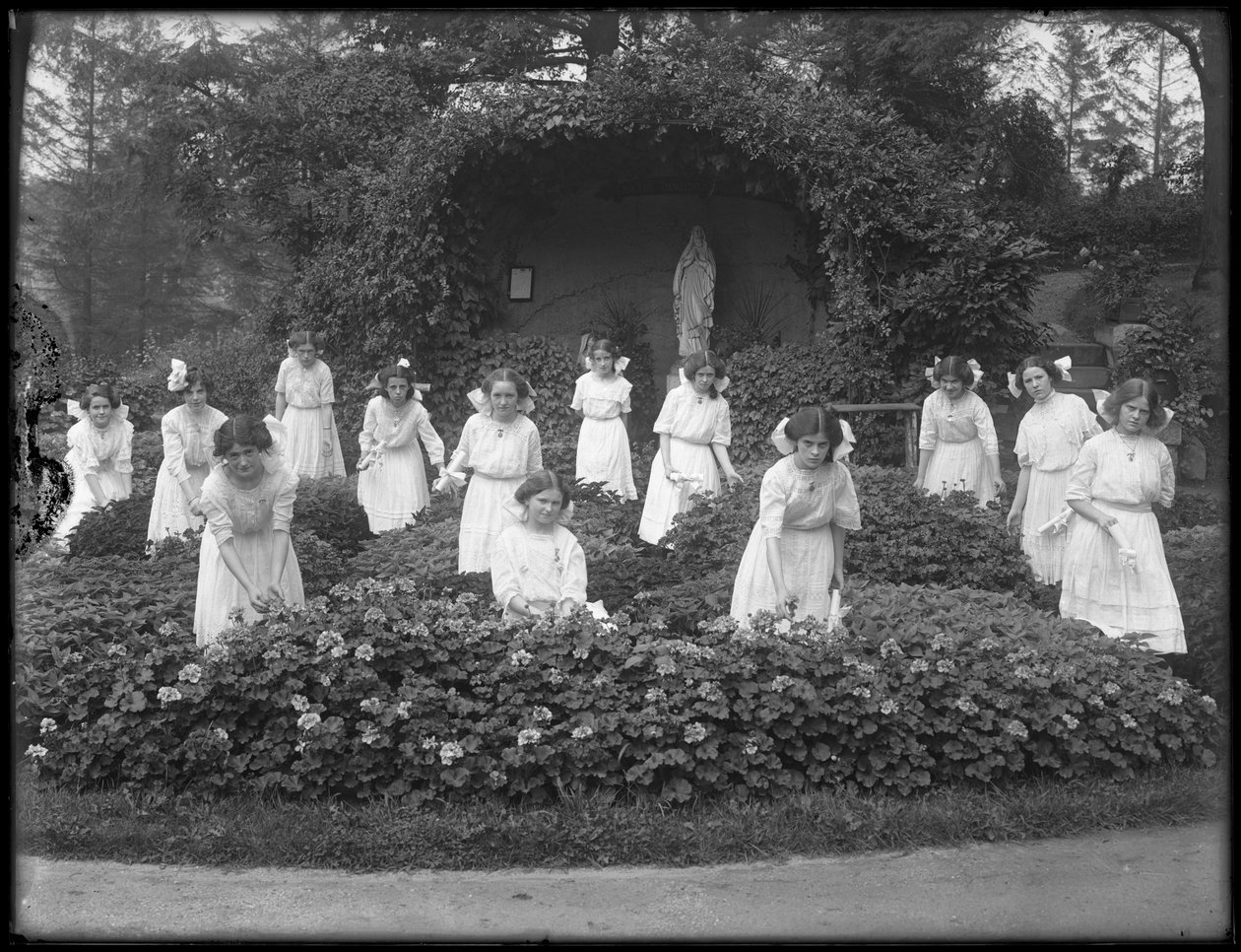 Avgångsklass av flickor från den romersk-katolska föräldralösa asylen i blomsterträdgården, framför Jungfru Marias grotta, 1912 bw foto av William Davis Hassler