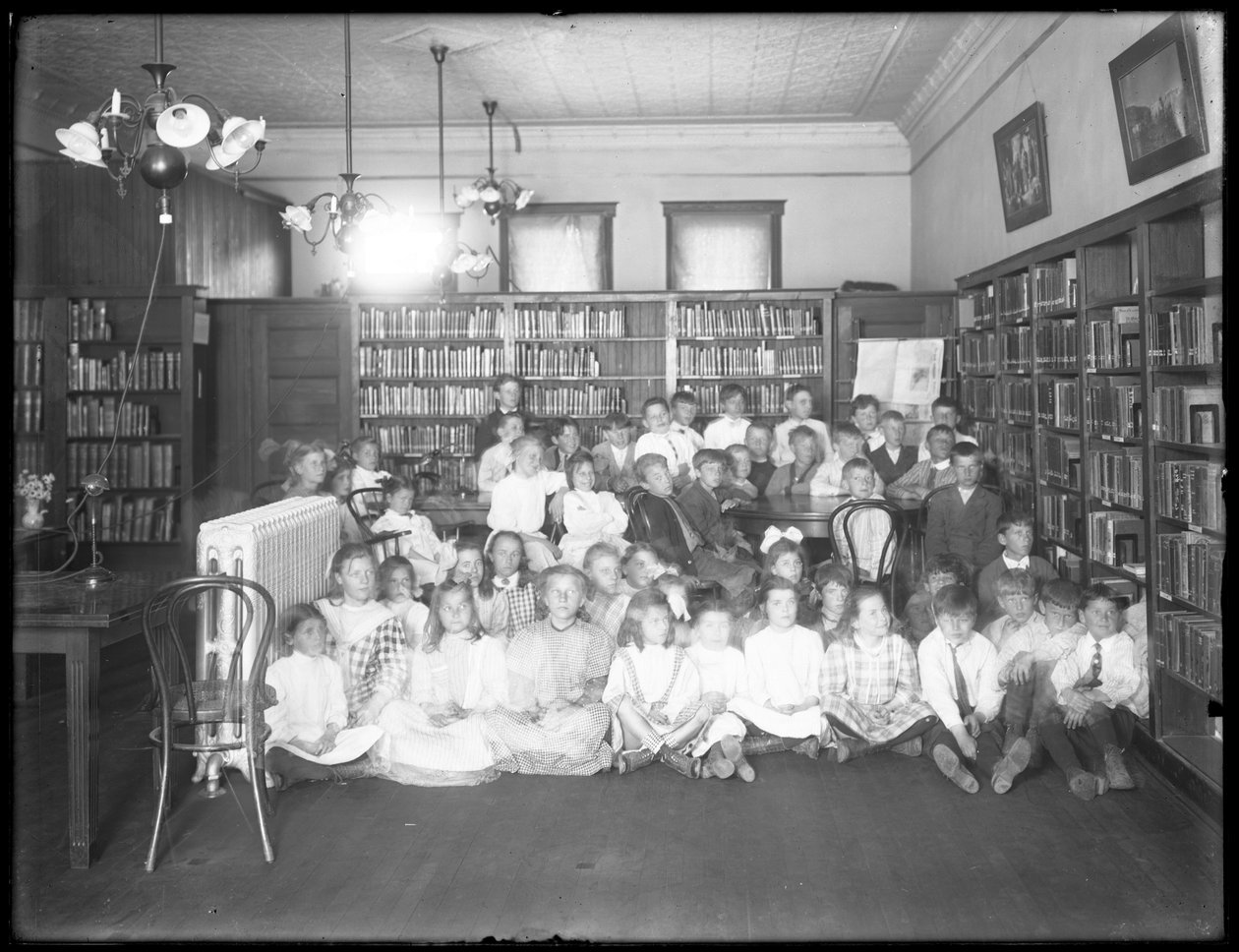 Gruppporträtt av barn i läsesalen i en oidentifierad filial av Queens Borough Public Library, ca 1910 av William Davis Hassler
