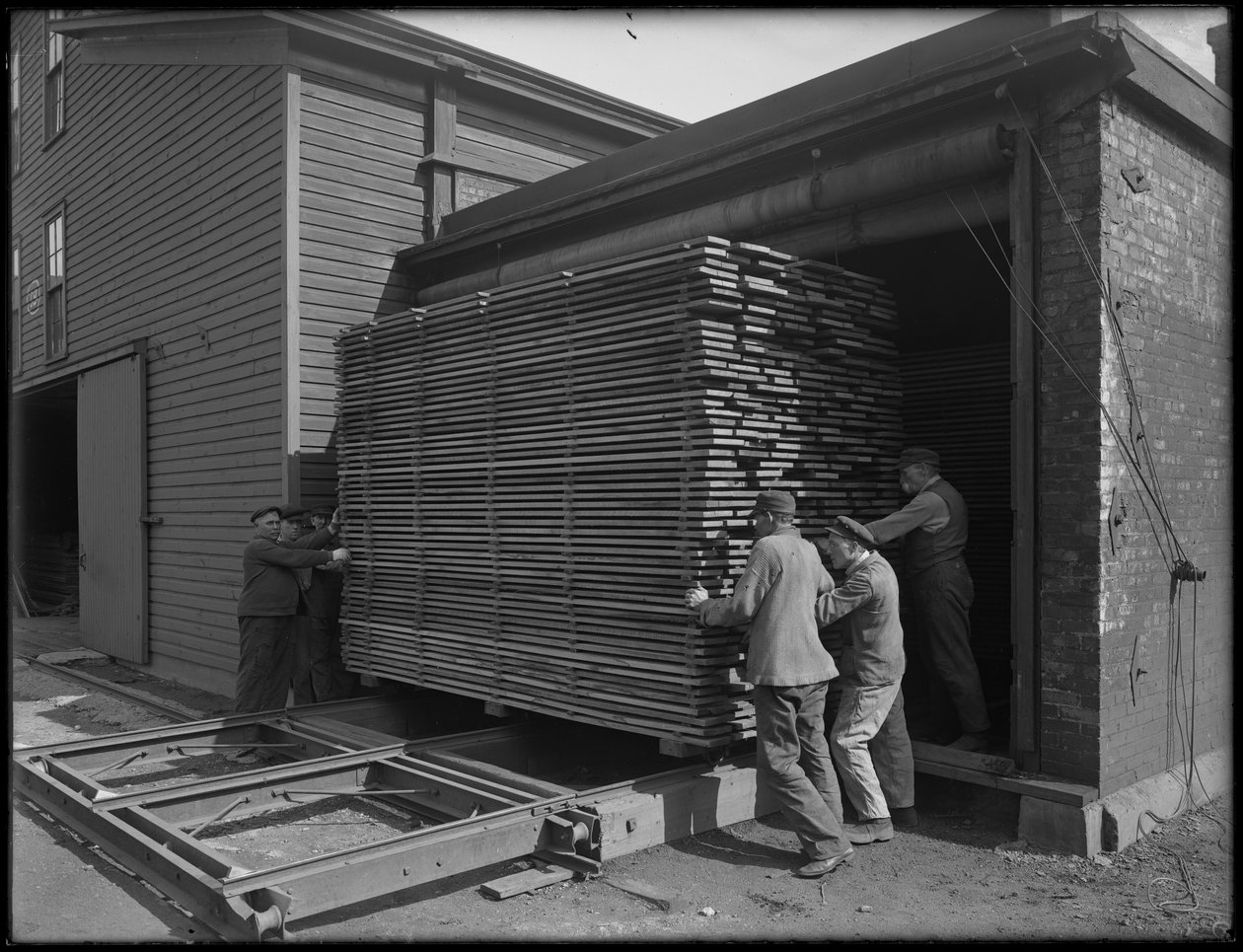Timmer som ska användas för tillverkning av kistor tas bort från torra ugnar, Oneida, New York, 3 april 1916. av William Davis Hassler