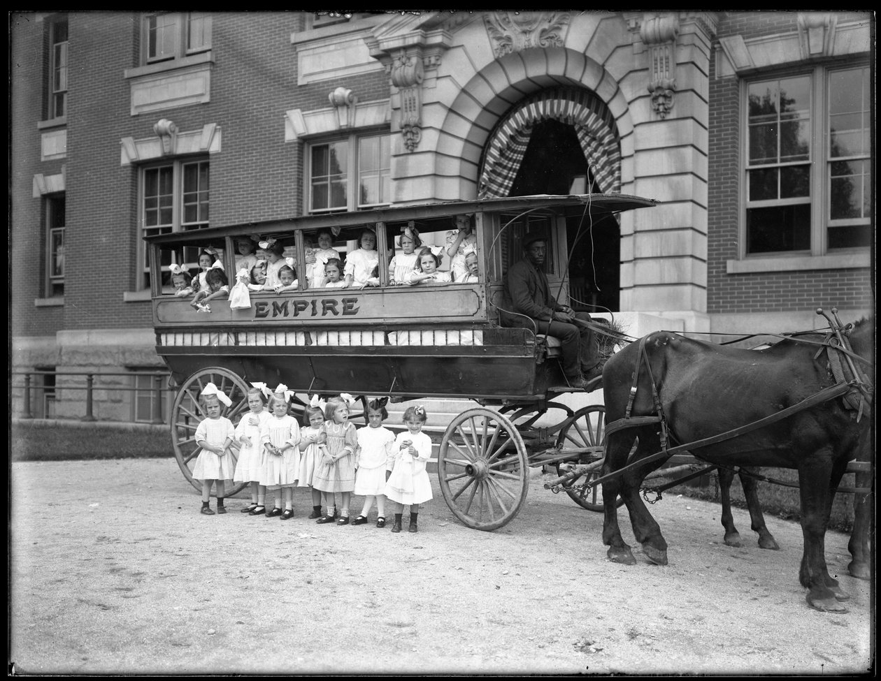 Små flickor poserar i och framför en hästdragen vagn, framför en oidentifierad byggnad, troligen den romersk-katolska föräldralösa asylen, Kingsbridge, Bronx, ca 1910 av William Davis Hassler