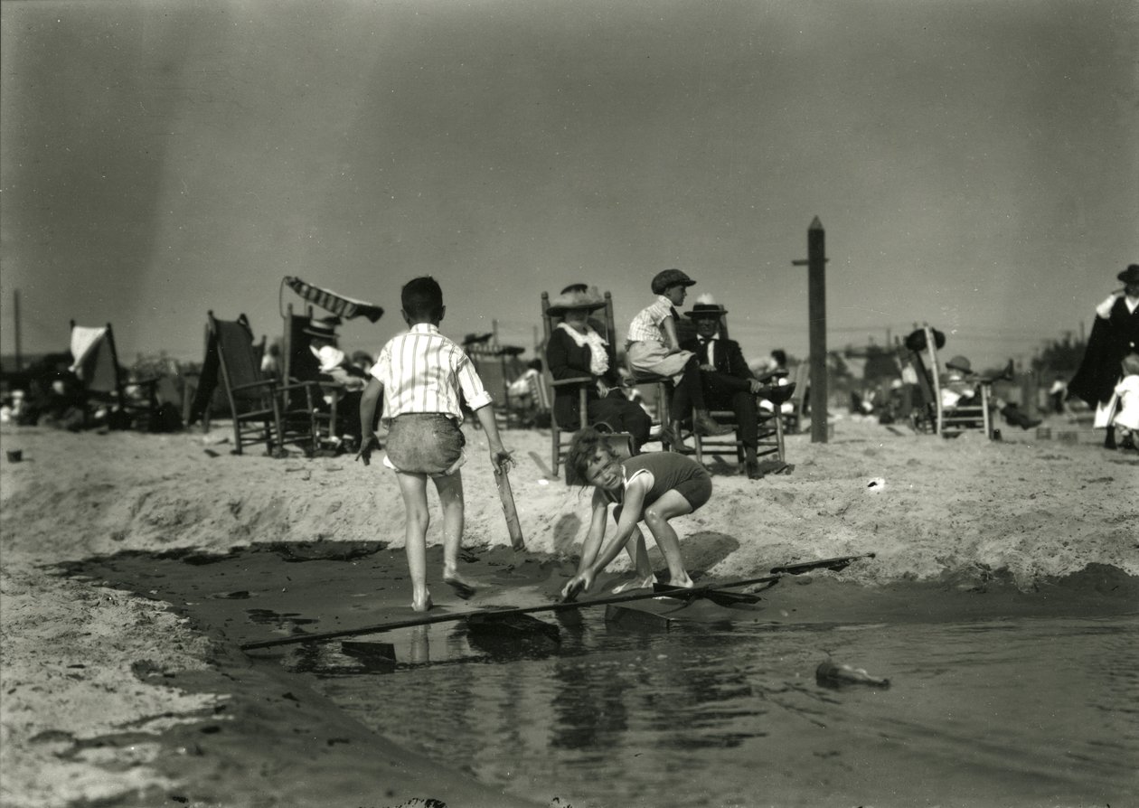 Två barn leker med trärester i grunt vatten, Coney Island, ca 1910-21 av William Davis Hassler