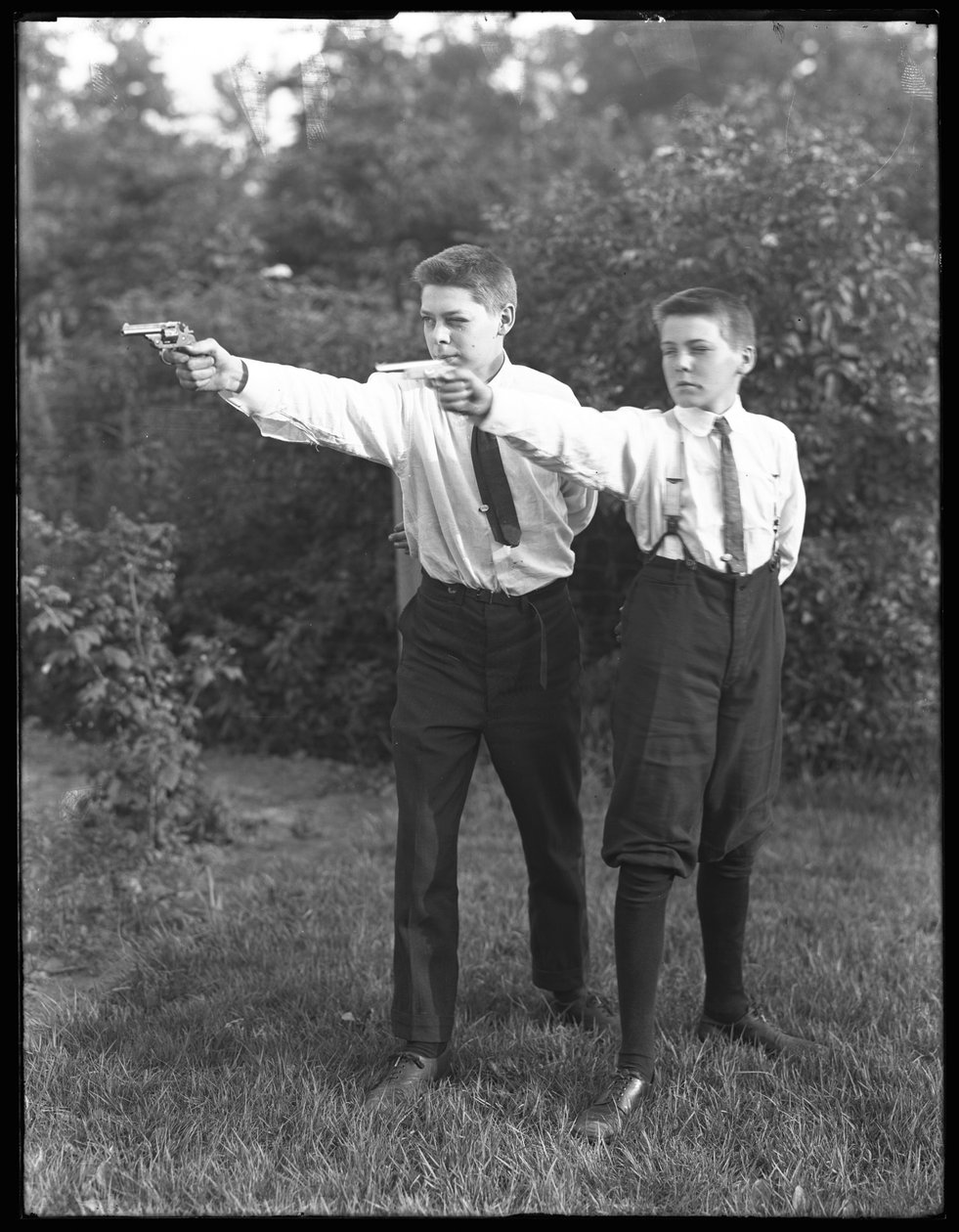 Två oidentifierade pojkar poserar med pistoler i sikte, juli 1915 av William Davis Hassler