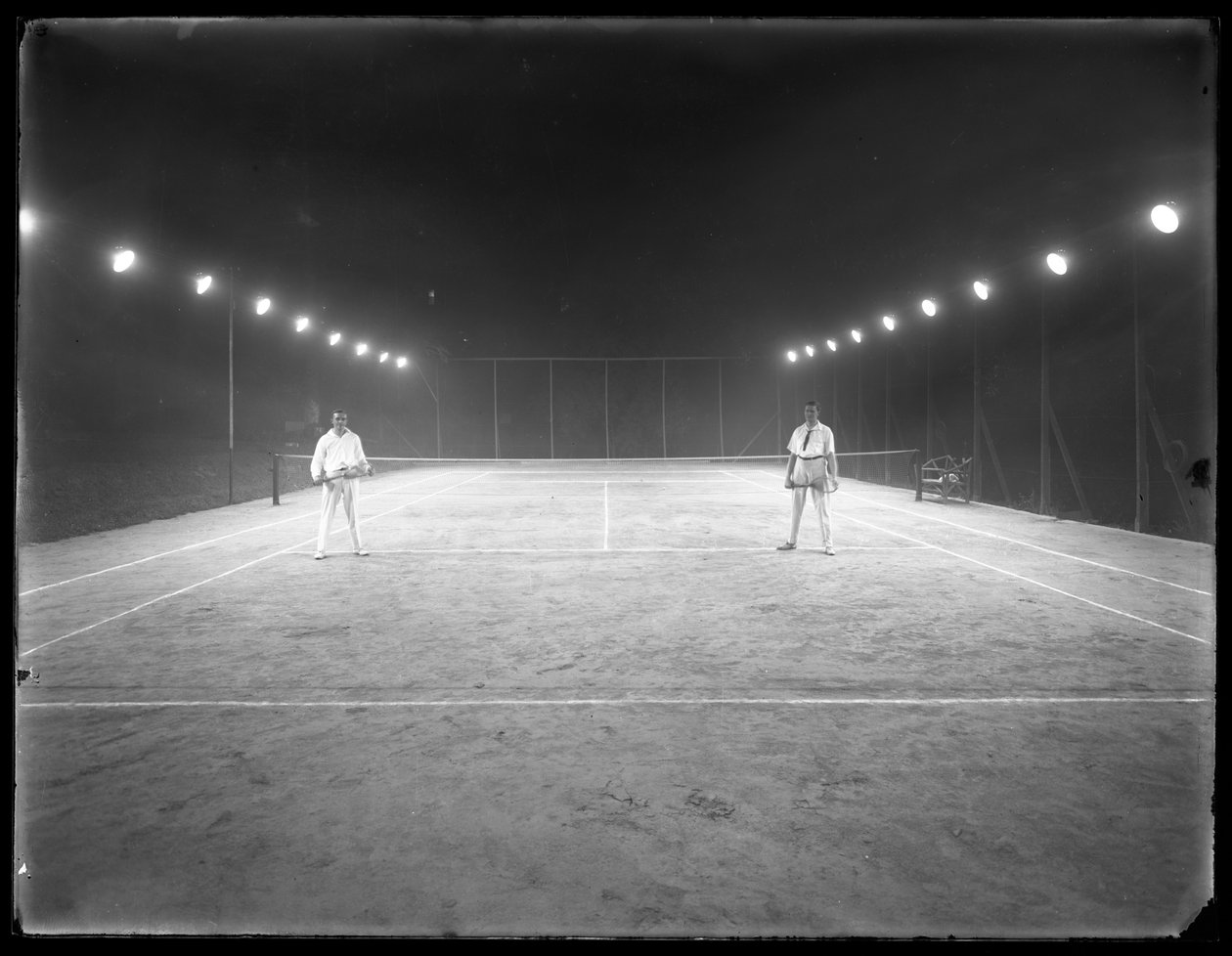 Två unga män på en oidentifierad tennisbana på natten, juli 1915 av William Davis Hassler