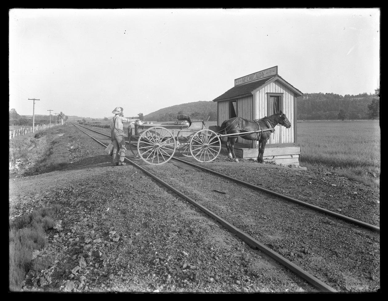 Oidentifierad man lastar mjölk på hästdragen vagn parkerad över järnvägsspår utanför McCready farm, Pennsylvania, ca 1913 av William Davis Hassler