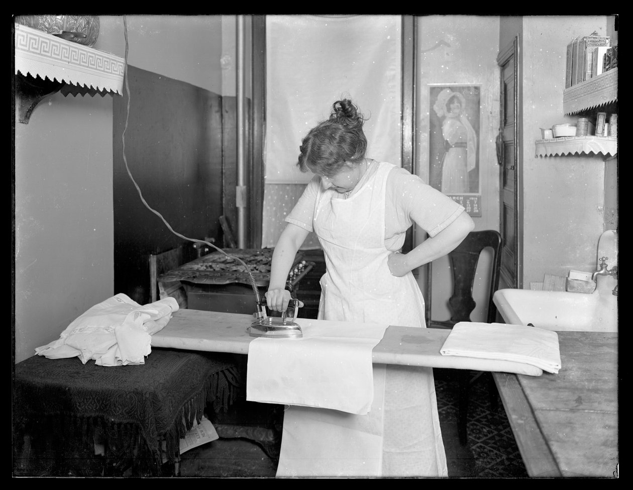 Oidentifierad kvinna som visar hur man använder ett elektriskt strykjärn c.1913-14 av William Davis Hassler