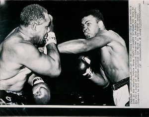 Unge Cassius Clay gör mål med vänster mot veteranen Archie Moore i den första omgången av kampen i Los Angeles av American Photographer