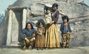 Vykort av en indisk familj från Navajo utanför deras hus eller "hogan" av American School