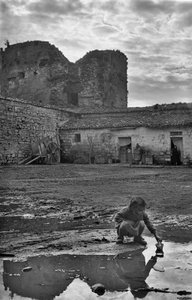 Ung flicka leker med en pappersbåt i en pöl omgiven av lera, Venosa, Basilicata, Italien