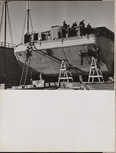 [En grupp män arbetar på en båt som ligger i hamn]