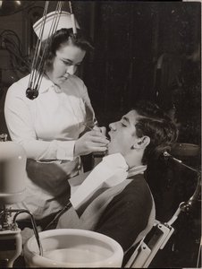 [Tandhygienist inspekterar en patients mun] av Arnold Eagle