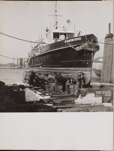 [Fyra män reparerar den nedre halvan av en båt som ligger i hamn] av Arnold Eagle