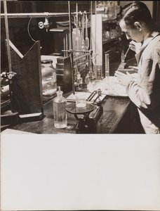 [En man i ett laboratorium använder båda händerna för att placera en stor pipett i en bägare]. av Arnold Eagle